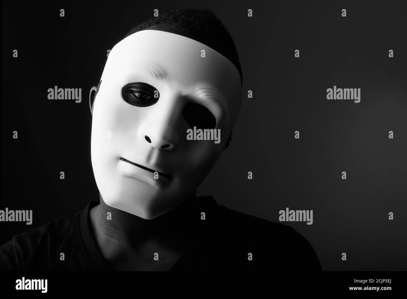 Studio shot von jungen schwarzen afrikanischen Mann im dunklen Zimmer tragen Maske Stockfoto