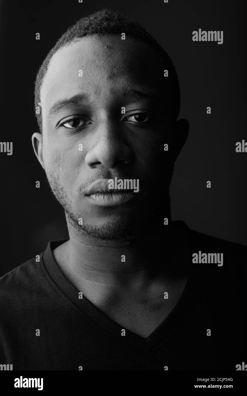 Studioaufnahme eines jungen schwarzen afrikanischen Mannes im dunklen Raum Stockfoto