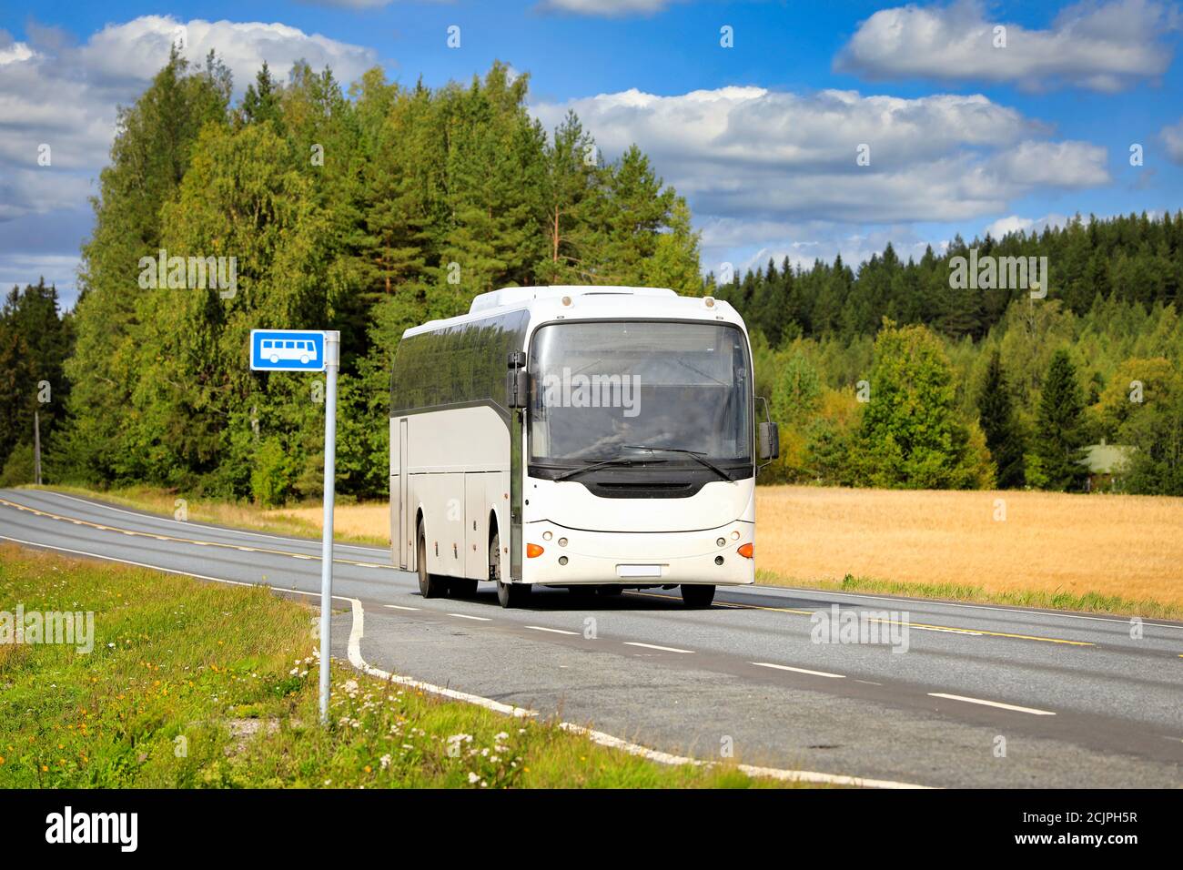 Weißer Reisebus fährt auf der Autobahn durch die Landschaft an einem schönen Sommertag. Stockfoto