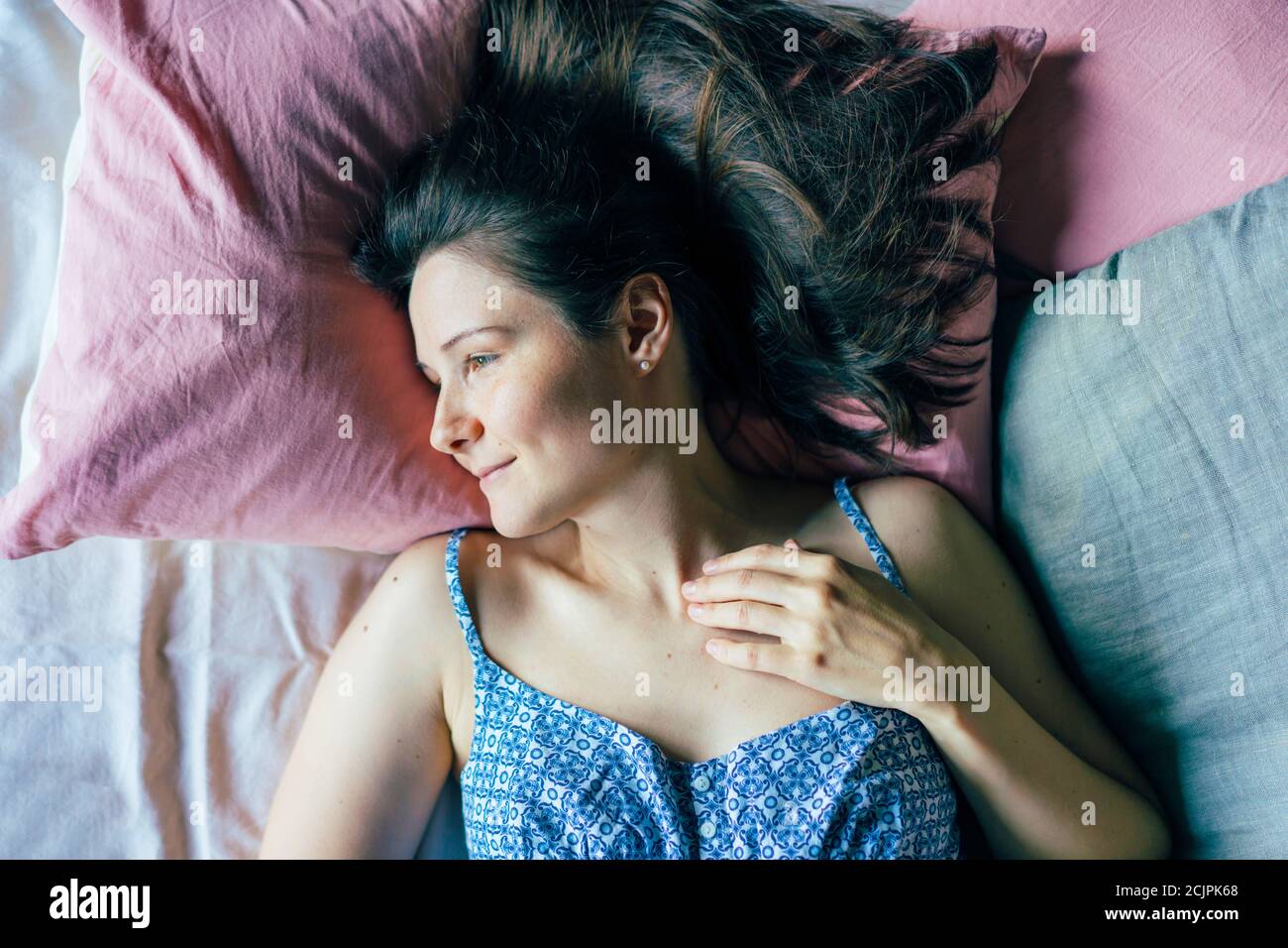 Junge Frau nach dem Aufwachen am Morgen liegt auf dem Bett. Stockfoto