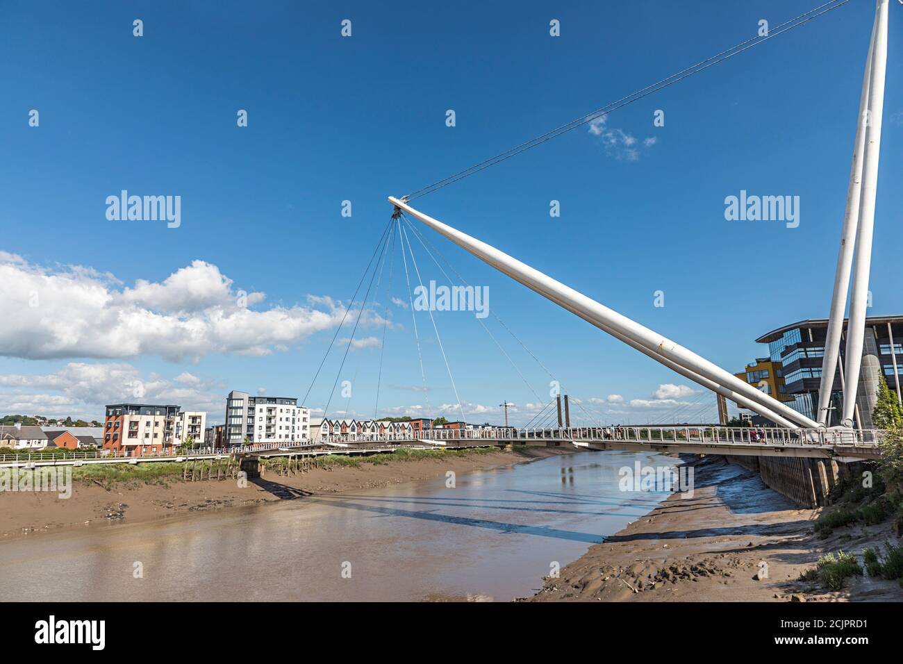 Fußbrücke und Wohnsiedlung am Flussufer mit Gezeitenfluss, Newport, Wales, Großbritannien Stockfoto