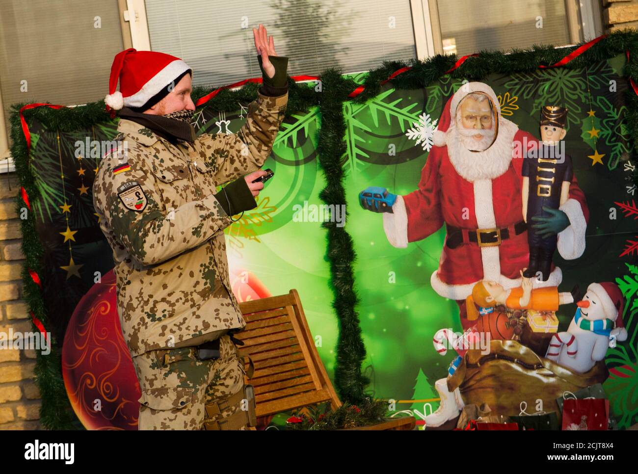 Ein Soldat der deutschen Kontingenz von der International Assistance (ISAF) trägt einen Weihnachtsmann, als er vor eine weihnachtliche Fotowand im Camp Marmal in der Nähe der nördlichen Stadt Mazar-e-Sharif 21. Dezember 2011 steht.   REUTERS/Thomas Peter (AFGHANISTAN - Tags: Unruhen militärische Politik) Stockfoto
