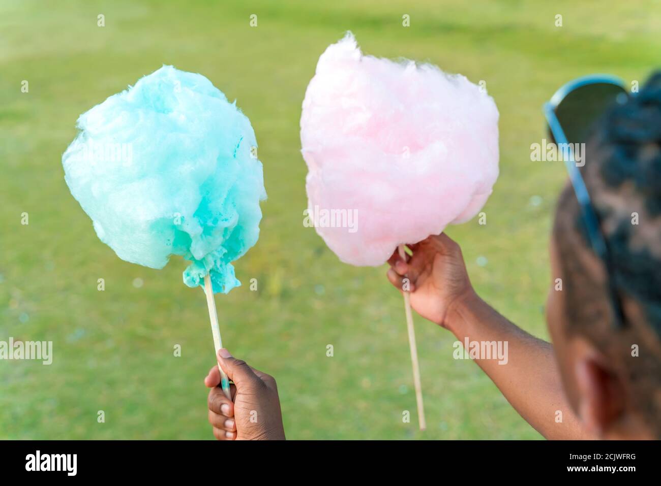 Ein glückliches schwarzes Paar, das bunte Zuckerwatte zusammen in einem Park einer großen Stadt hat. Stockfoto