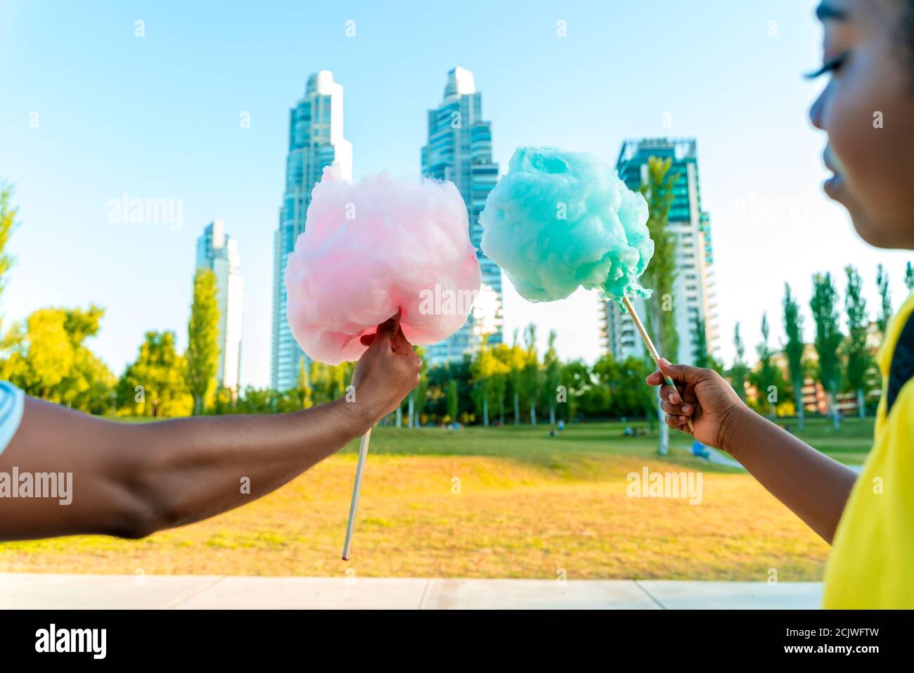 Ein glückliches schwarzes Paar, das bunte Zuckerwatte zusammen in einem Park einer großen Stadt hat. Stockfoto
