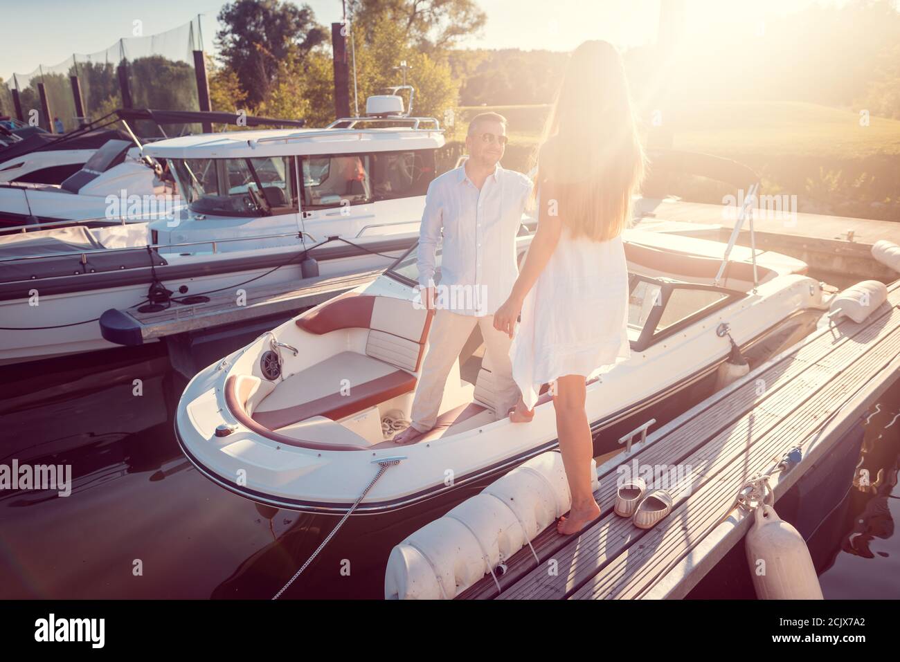 Mann lädt eine Frau zu seinem Motorboot im Flusshafen sitzen Stockfoto