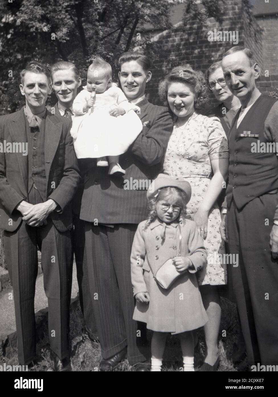 1950er Jahre, historisches Bild zeigt die Kleidung und Mode der Zeit als Familie stehen zusammen für ein Gruppenfoto, mit einem stolzen jungen Vater hält sein Kleinkind, England, Großbritannien. Stockfoto