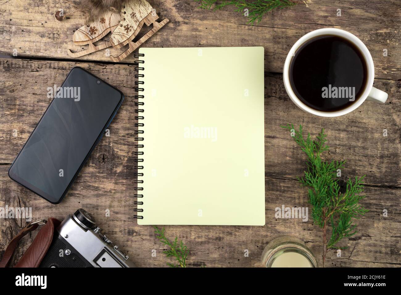 Notizblock, Nadelzweige, Kaffee und Sandwiches, Telefon und Retro-Kamera auf dem Hintergrund aus Naturholz. Stockfoto