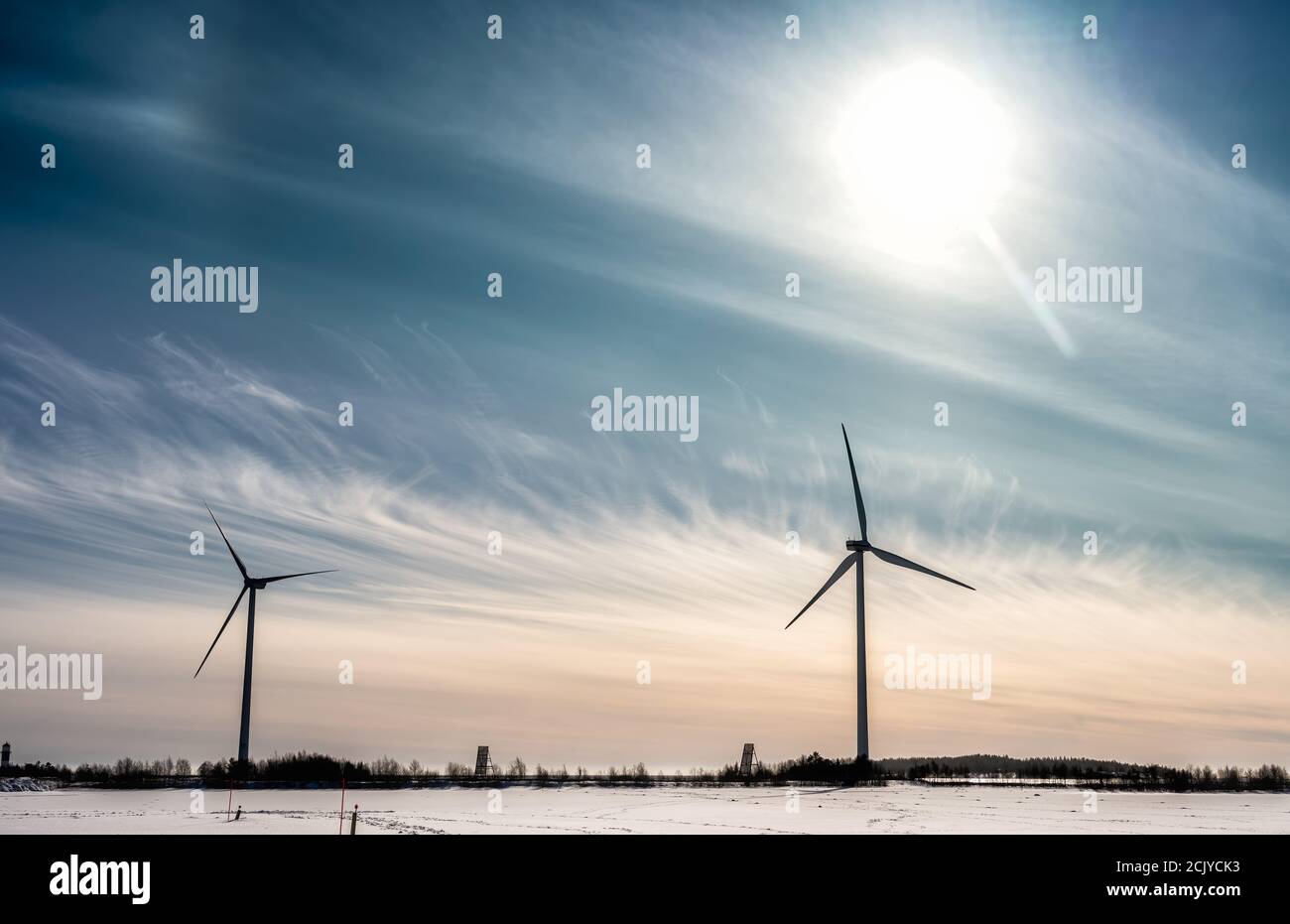 Zwei angestoppte Windmühlen, kein Wind. Gefrorene Küste der Ostsee. Große Sonne am Himmel mit blauen rosa Cirrus Licht Wolken. Kalter sonniger Tag an der Nordbaltischen Ostsee. Eco Stockfoto