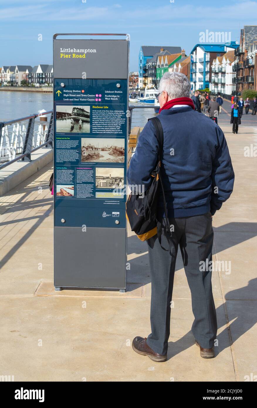 Mann, der an einem Hinweisschild mit historischen Informationen über Littlehampton, auf dem Schlepppfad in Pier Road, Littlehampton, West Sussex, England, Großbritannien, steht. Stockfoto