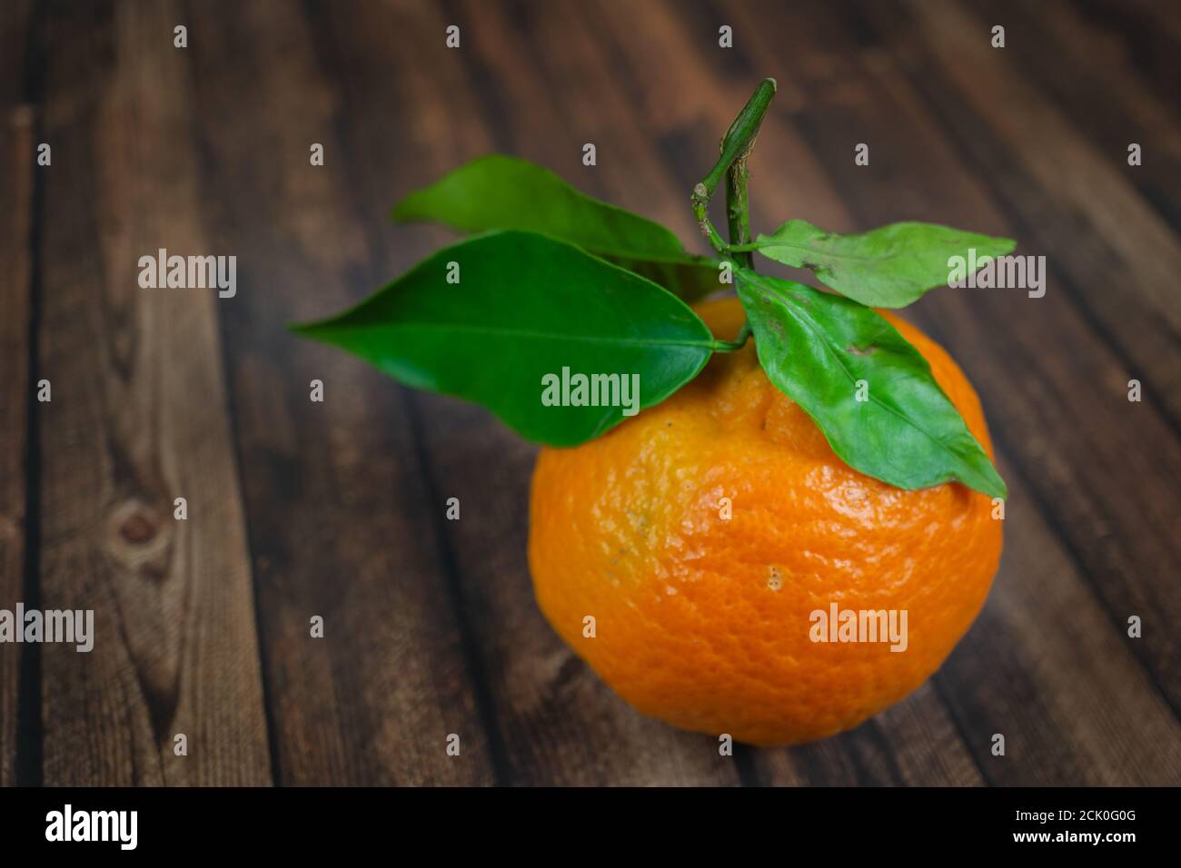 Nahaufnahme von frischer Mandarine mit grünen Blättern auf Holz Hintergrund Stockfoto