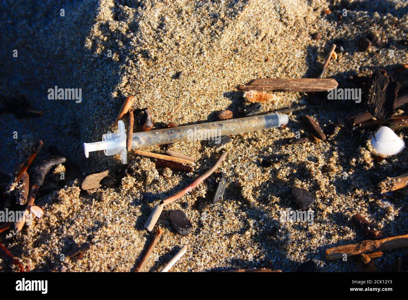 Gefährliche gebrauchte Spritzen am Strand in der Mitte verlassen Von anderem Schmutz und Müll Stockfoto