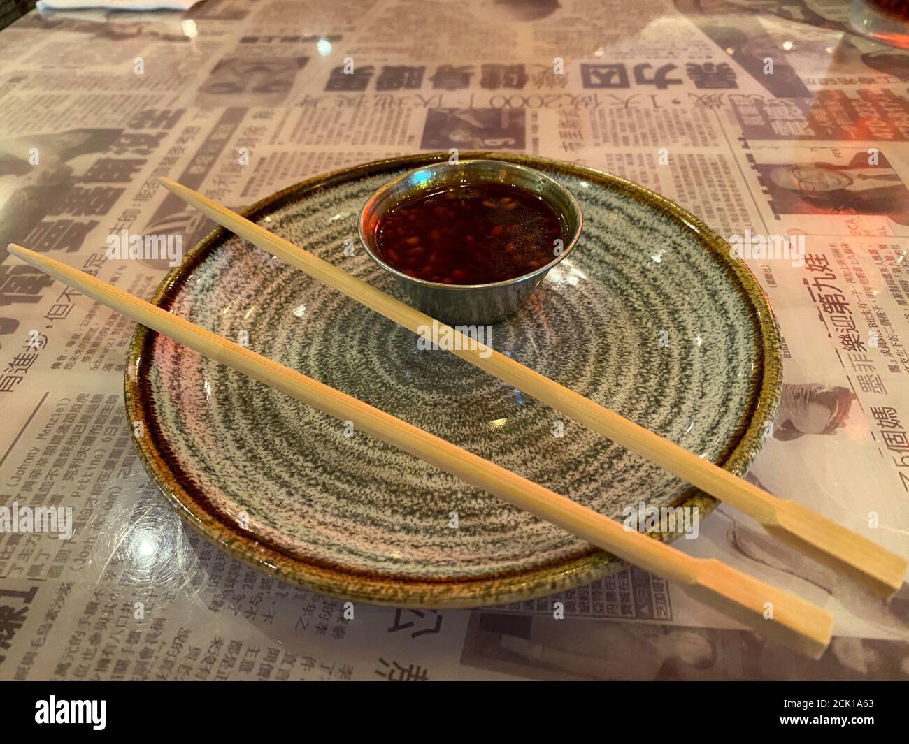 Ein Teller mit Essstäbchen und einem kleinen Behälter mit Soße, bereit für die Hauptgerichte, die in einem asiatischen Fusion-Restaurant serviert werden. Stockfoto