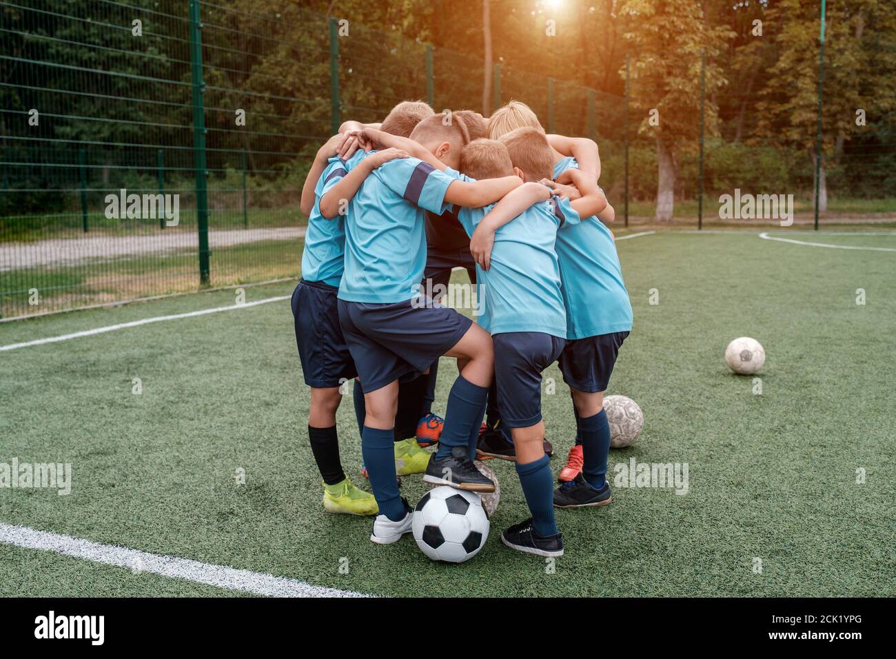 Kinder Fußballmannschaft und Trainer umarmt sich gegenseitig auf Fußball Feld vor Übereinstimmung Stockfoto