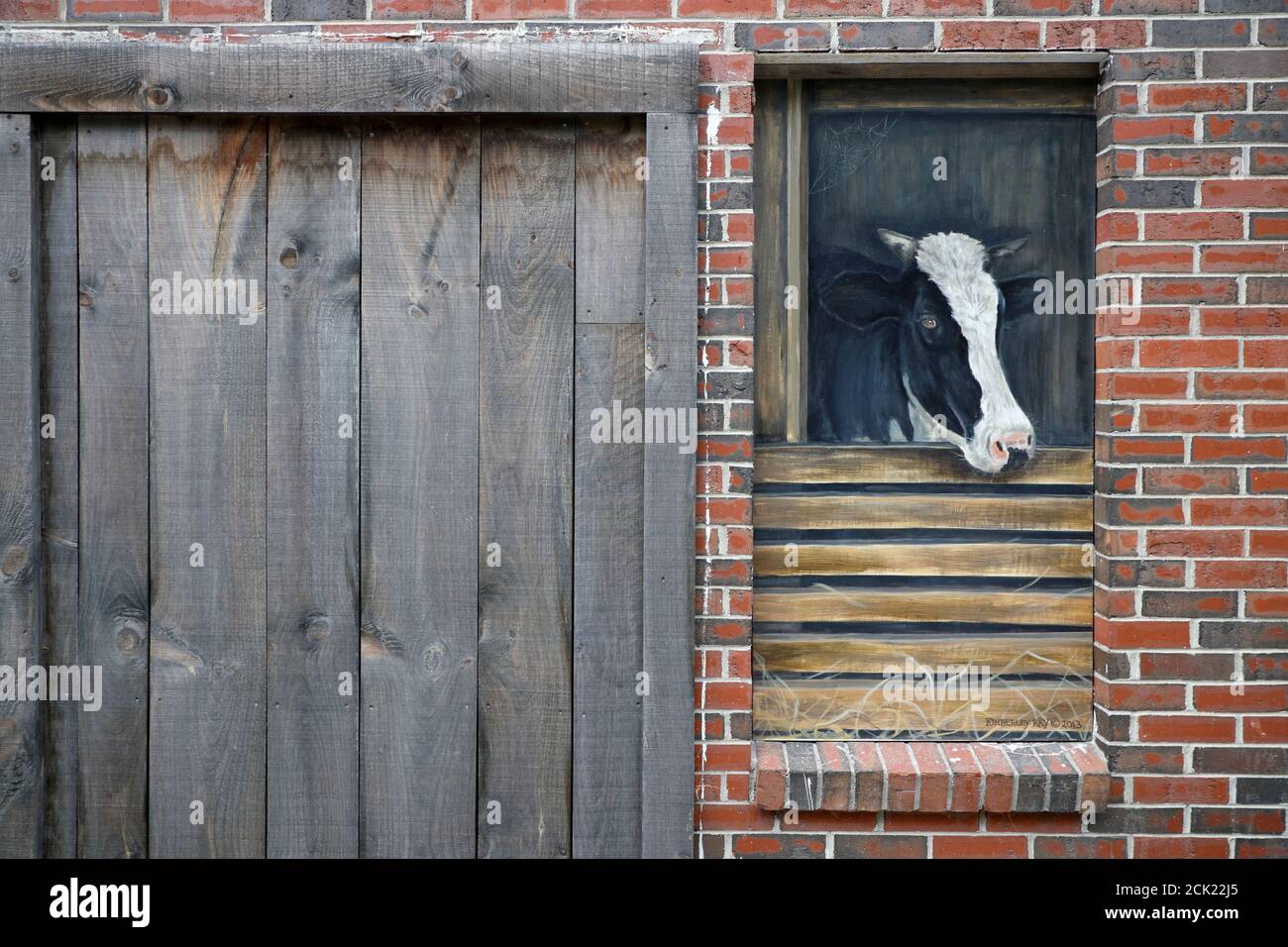 Ein Milchkuhgemälde schmückte eine Ladenwand daneben Eine Holztür.Londonderry.Vermont.USA Stockfoto