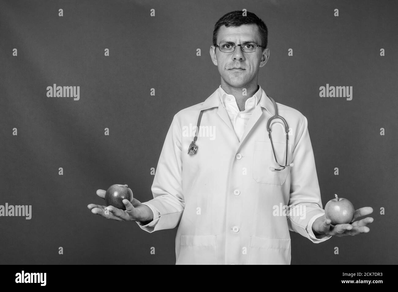 Schöner mann Arzt mit kurzen Haaren gegen grauer Hintergrund Stockfoto