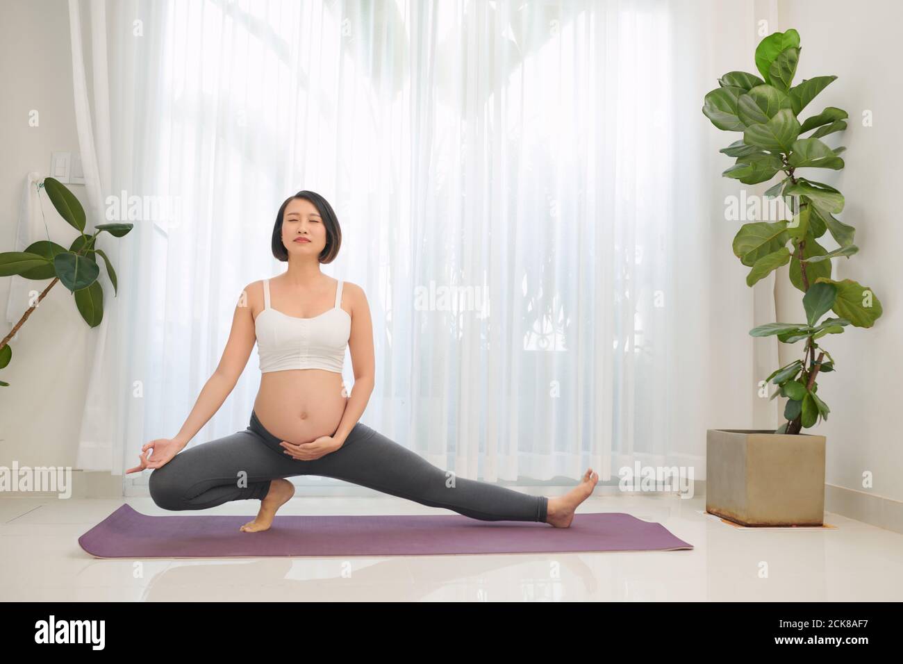 Portrait von schönen jungen schwangeren Yoga-Modell arbeiten innen. Stockfoto