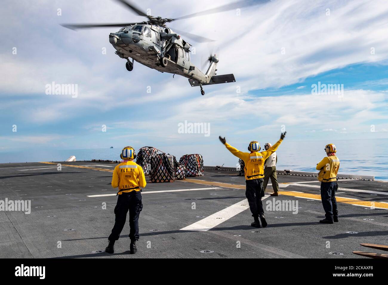 200914-N-RU810-1110 PHILIPPINISCHES MEER (SEPT 14, 2020) Seeleute, die dem nach vorne eingesetzten amphibischen Sturmschiff USS America (LHA 6) zugeordnet sind, signalisieren einen MH-60S Sea Hawk Hubschrauber, der den Erzengeln des Helicopter Sea Combat Squadron (HSC) 25 Detachment 6 während einer Auffüllung auf See mit dem Trockenfracht- und Munitionsschiff USNS Washington Chambers (T-AKE 11) zugeordnet ist. America, das führende Schiff der America Amphibious Ready Group, die zusammen mit der 31. Marine Expeditionary Unit dem Amphibious Squadron Eleven zugewiesen wurde, ist im Verantwortungsbereich der 7. US-Flotte tätig, um die Interoperabilität mit A zu verbessern Stockfoto
