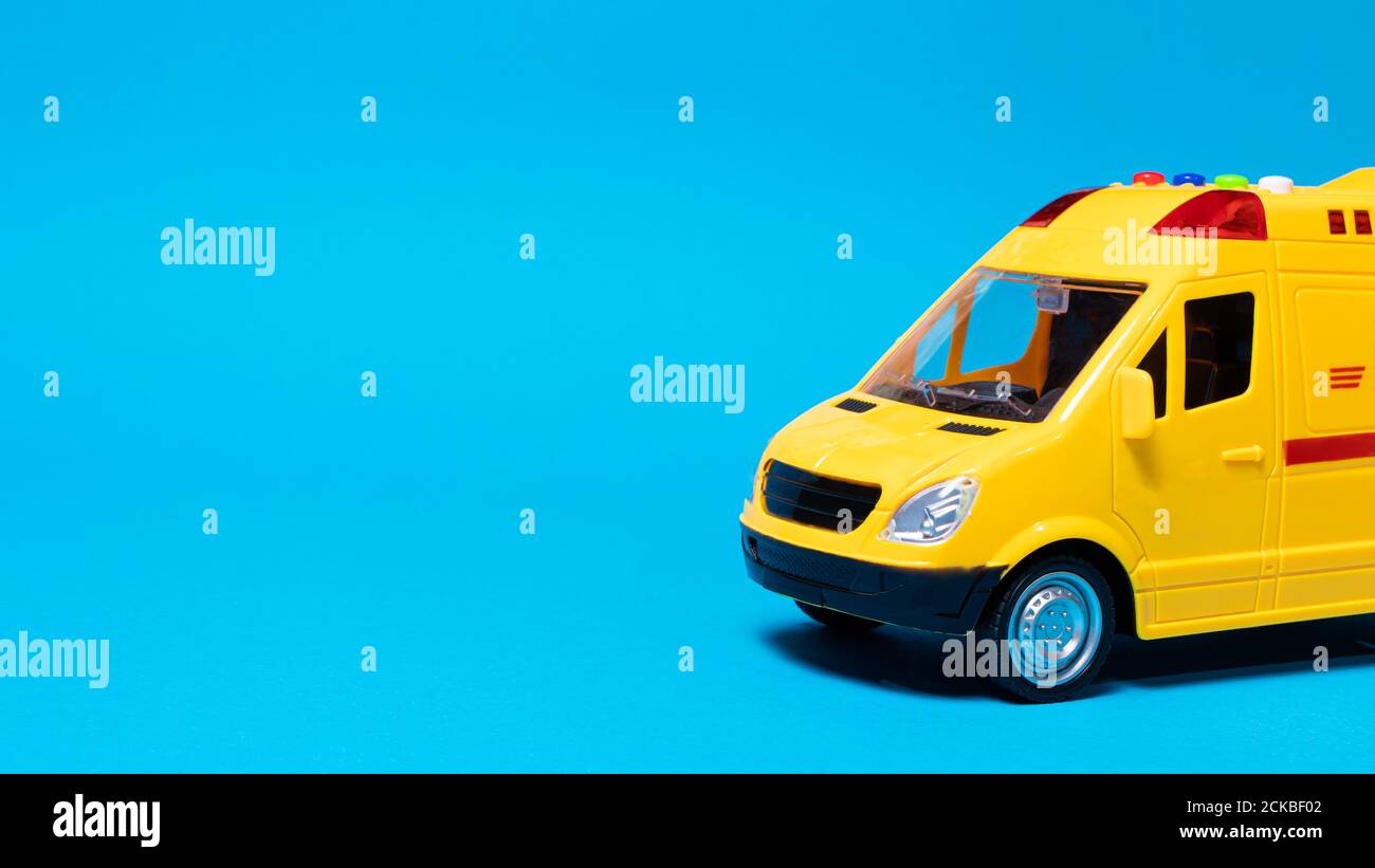 Gelber Spezial-Spielzeugauto-Postbus mit blinkenden Lichtern auf blauem Hintergrund. Lieferung der Post mit einem Ort, um den Text der Copyspace-Banner Stockfoto