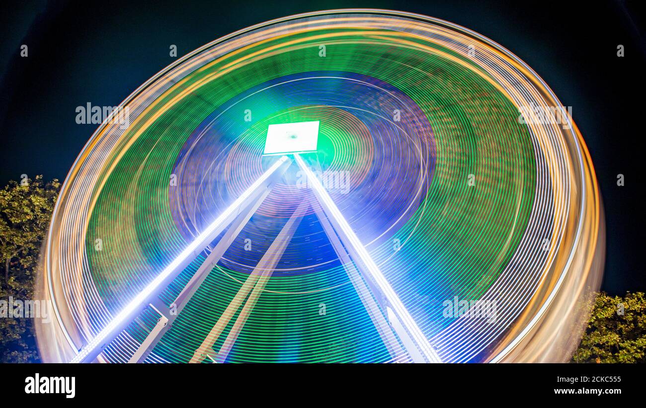 Die Fähren drehen sich nachts mit Lichtern im Vergnügungspark. Langzeitbelichtung. Stockfoto