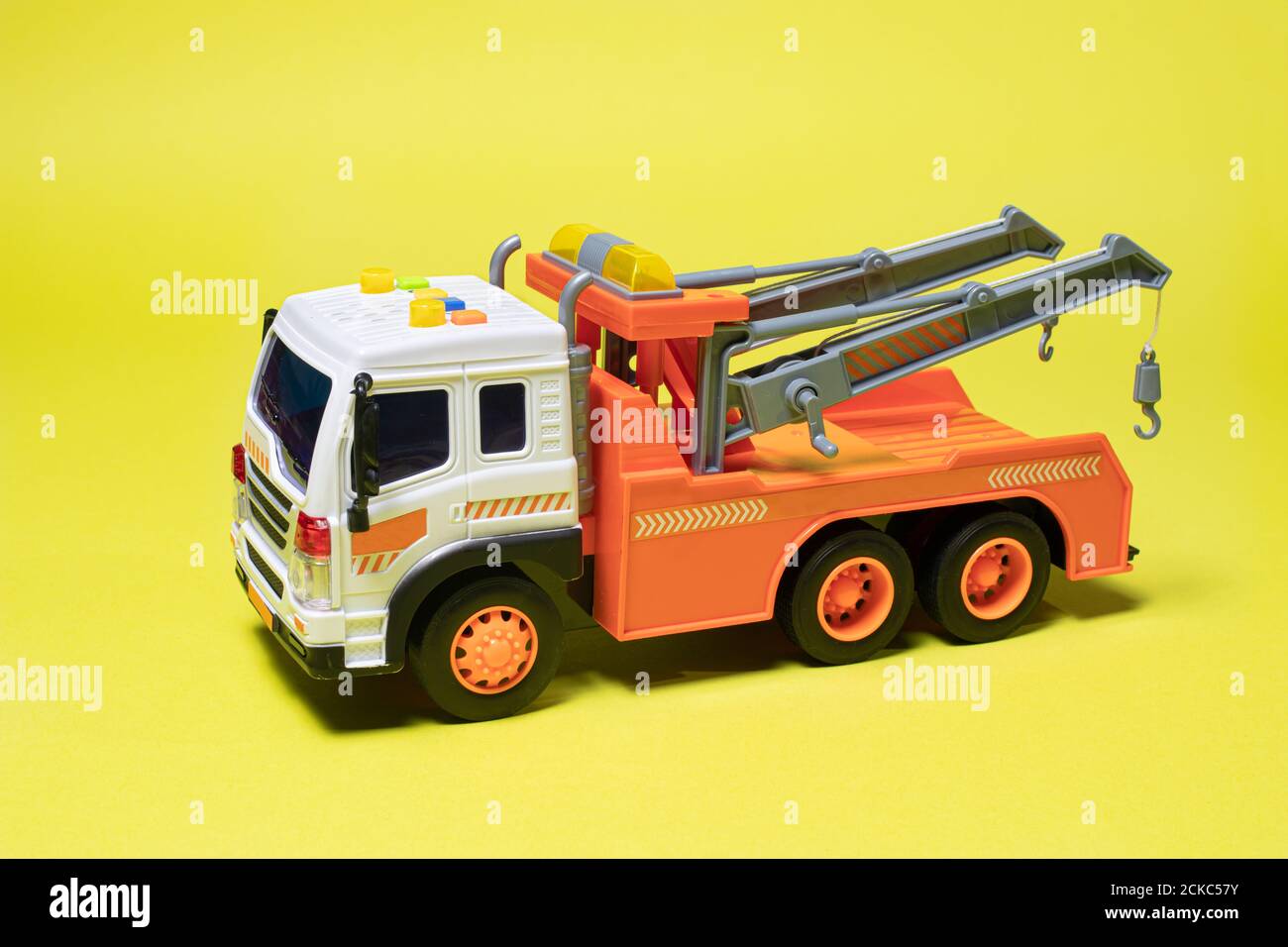 Spielzeug orange Abschleppwagen auf gelbem Hintergrund Banner mit Platz für Text. Kinderwagen zum Verladen und Transportieren von Autos Stockfoto