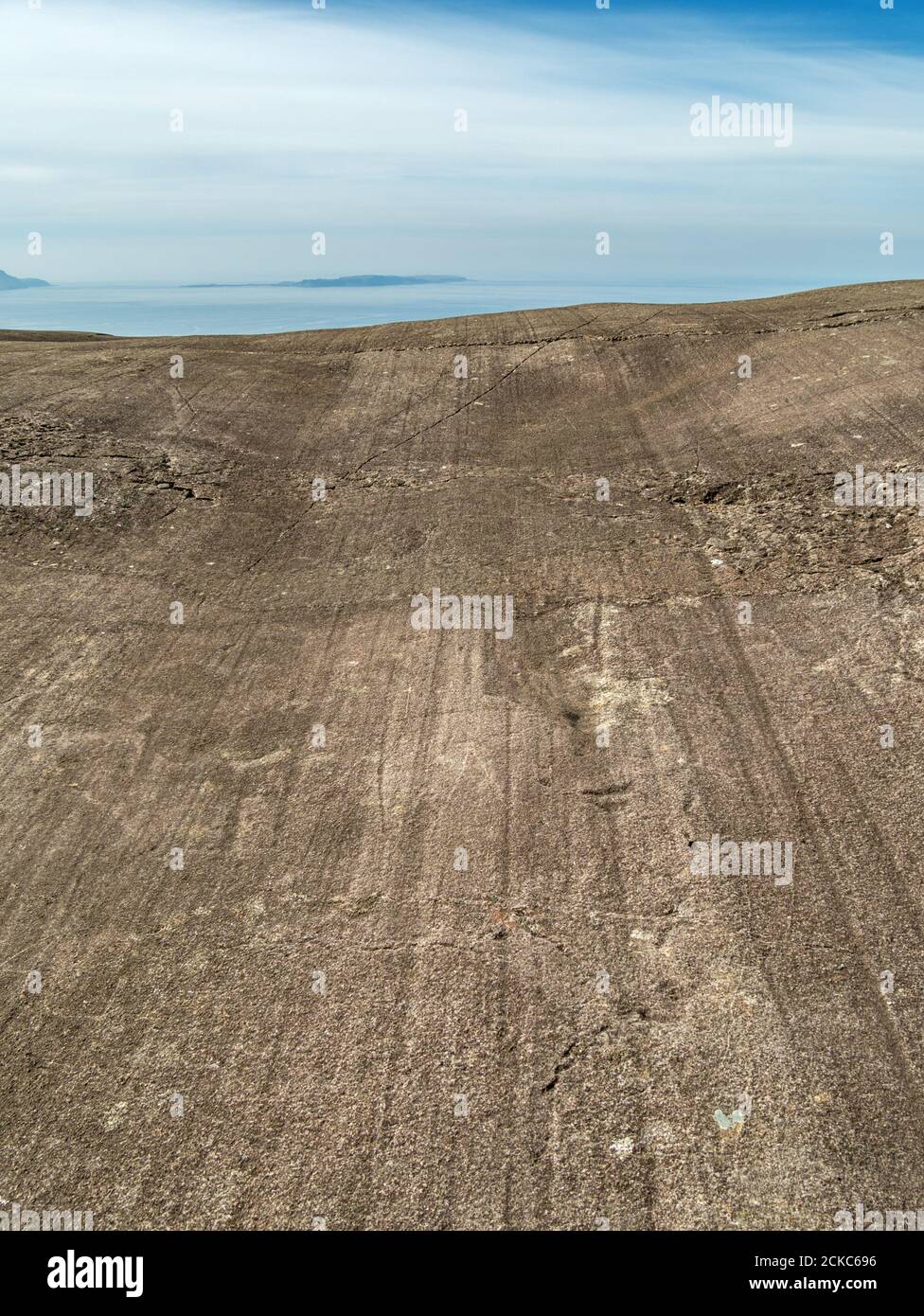 Gletscherpolieren und Mineralschichtbänder von Gabbro bei Coire Lagan mit Inseln von Canna und Sanday in der Ferne, Black Cuillin, Skye, Schottland. Stockfoto