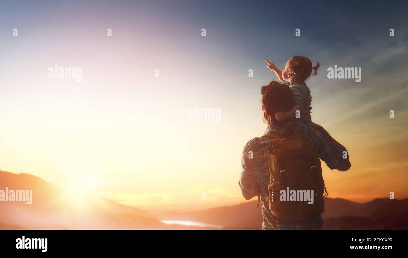 Glückliche Familie bei Sonnenuntergang. Vater und Tochter haben Spaß und genießen Reise. Baby sitzt auf den Schultern seines Vaters. Stockfoto