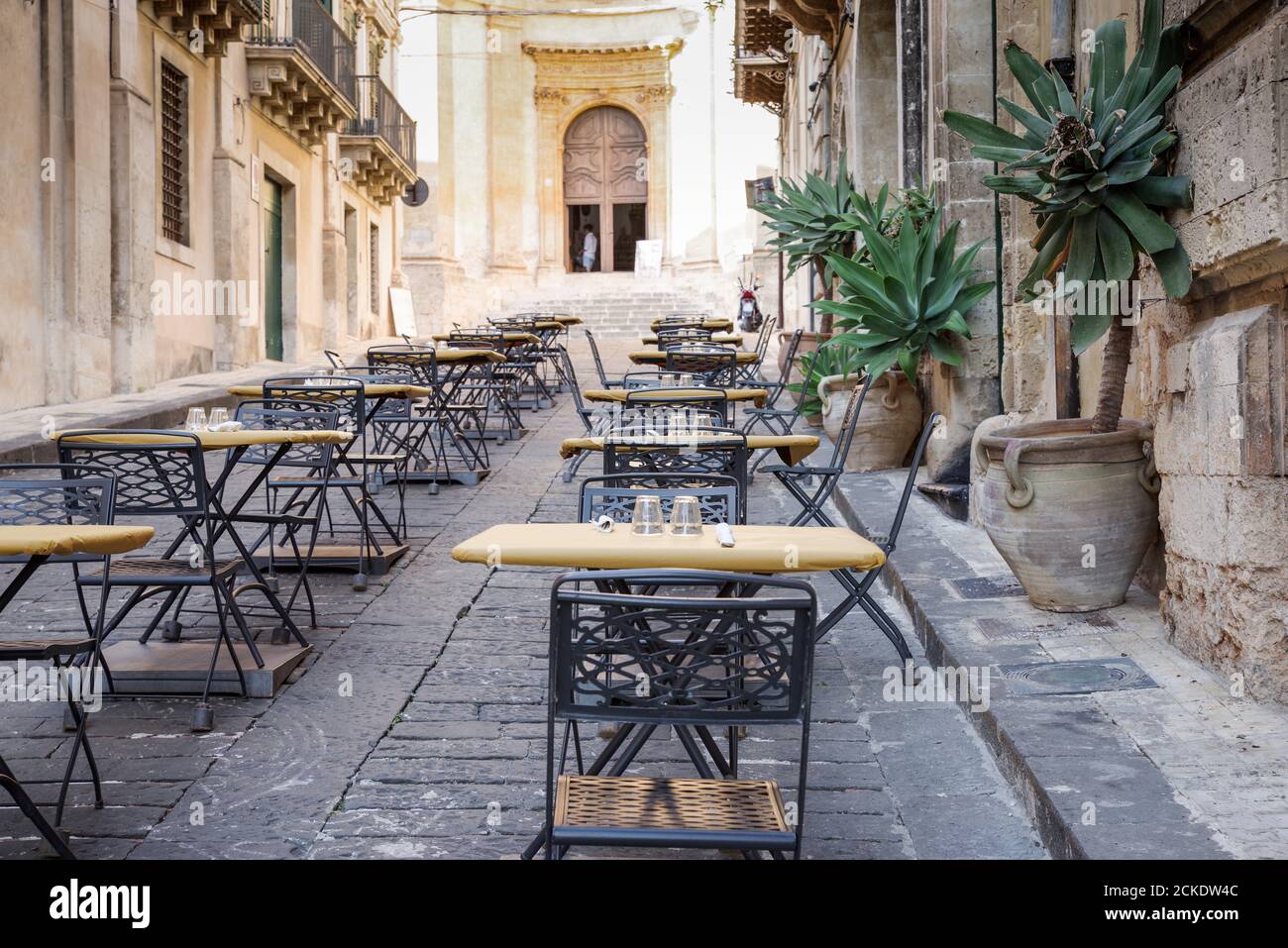 Hübsches Café mit Sitzgelegenheiten im Freien vor der Chiesa di Montevergine (auch bekannt als San Girolamo), einer barocken römisch-katholischen Kirche in Noto - Sizilien, Italien Stockfoto