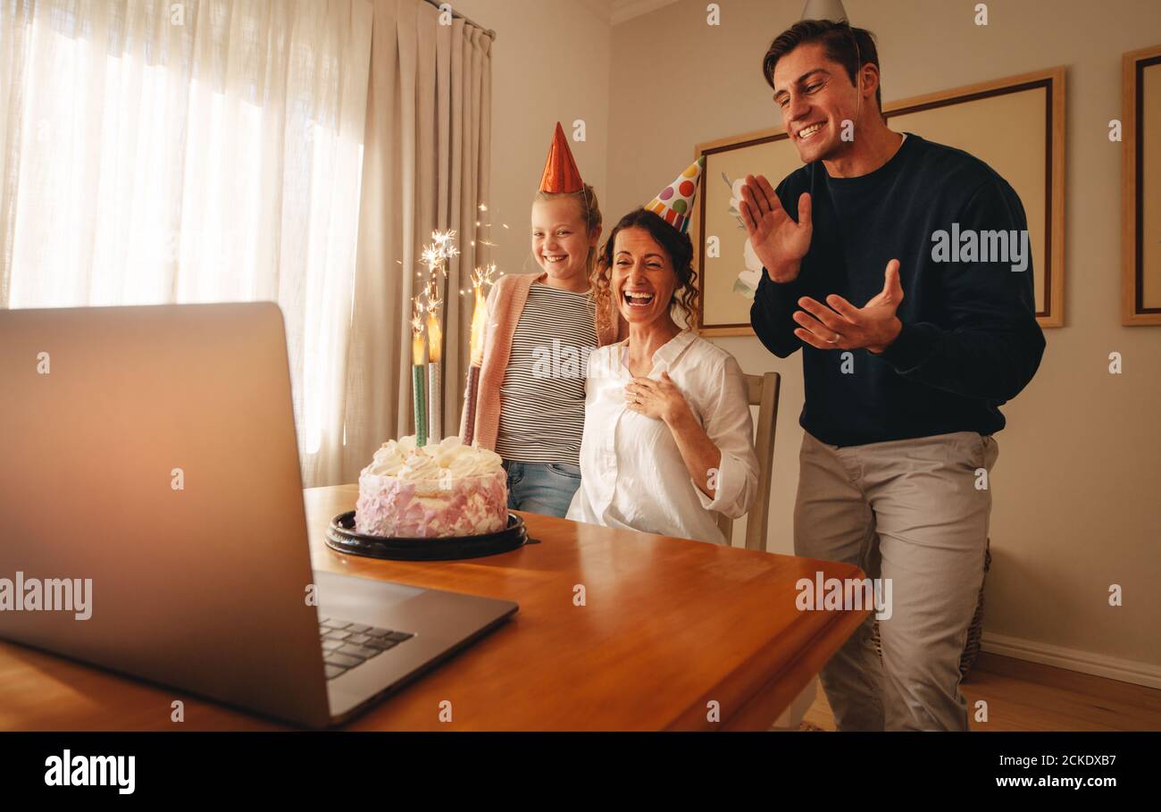 Frau feiert Geburtstag zu Hause mit Familie und Freunden auf Videoanruf. Familie feiert Mutter Geburtstag online. Stockfoto
