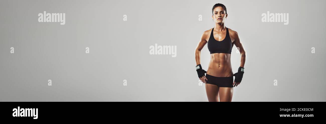 Portrait einer starken Frau mit entschlossener Optik. Weiblich mit starken bauchmuskeln und einem schlanken Körper. Panoramakultur. Stockfoto