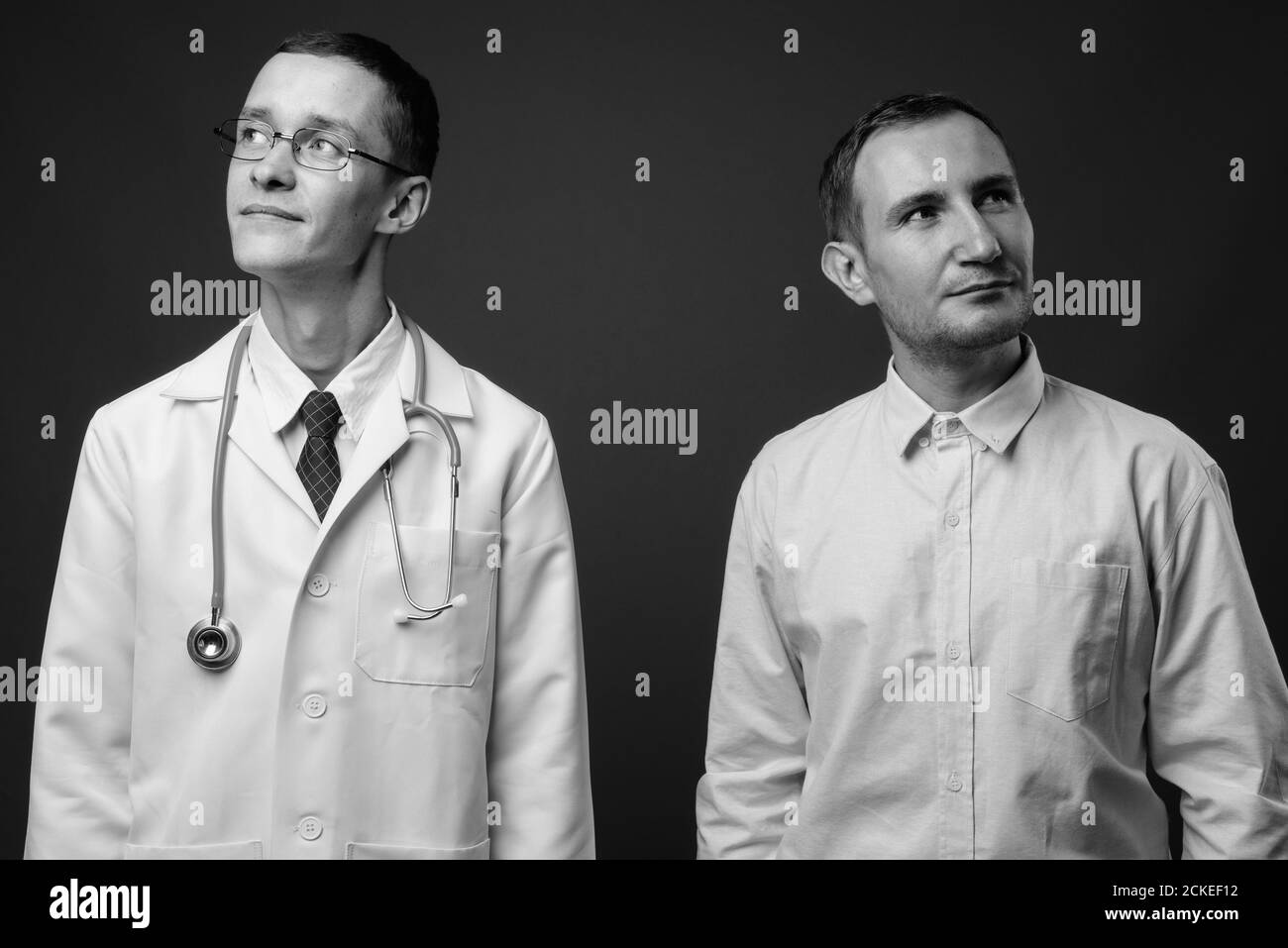 Junger Mann Arzt und Mann Patient vor grauem Hintergrund Stockfoto