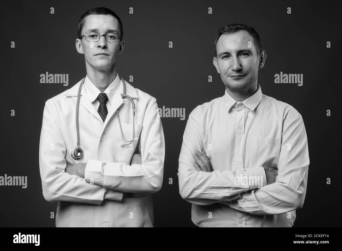 Junger Mann Arzt und Mann Patient vor grauem Hintergrund Stockfoto