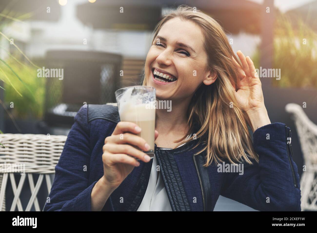 Junge attraktive fröhliche Frau genießen Kaffee Latte im Café im Freien Terrasse Stockfoto