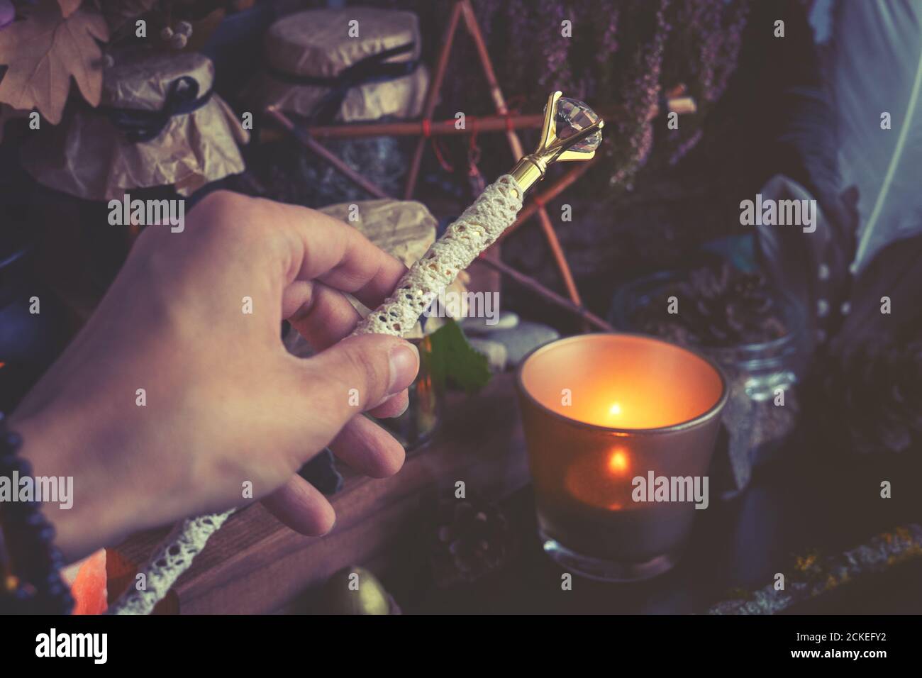 Frau Hand hält Zauberstab Durchführung einer heidnischen Hexe Ritual. Getönte bis kalte Farben Stockfoto