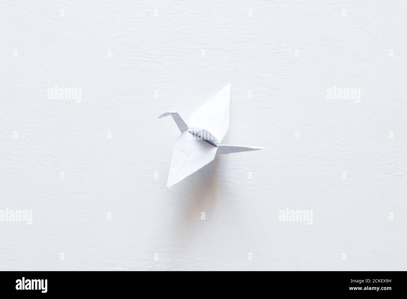 Papier Origami Kran auf weißem Hintergrund. Weltkranentag Stockfoto
