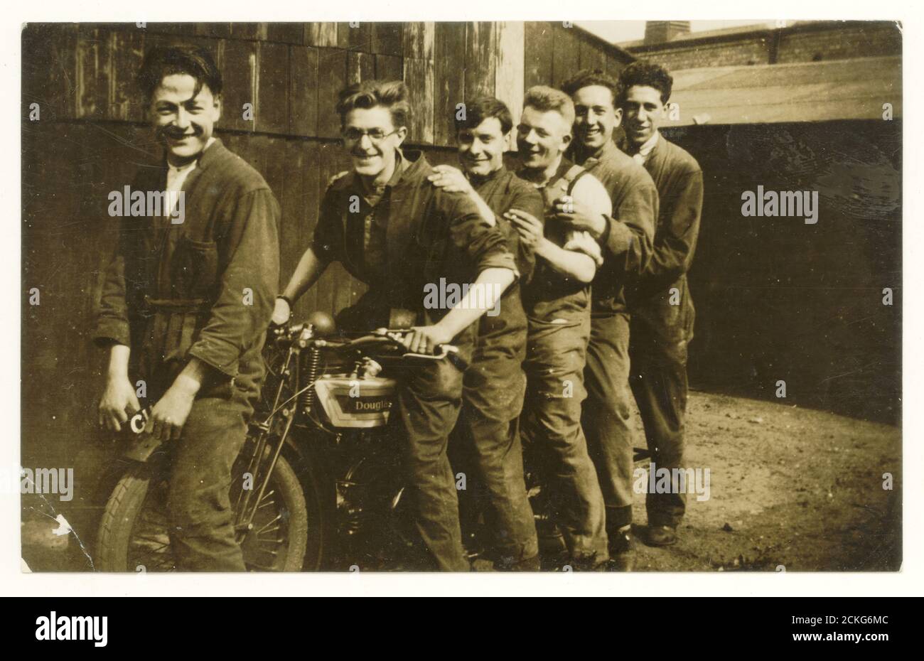 Originalpostkarte aus dem frühen 20. Jahrhundert mit glücklichen Motorradmechanikern und Douglas-Motorrad, die für ein Foto herumschwirren, um 1930er Jahre, Großbritannien Stockfoto