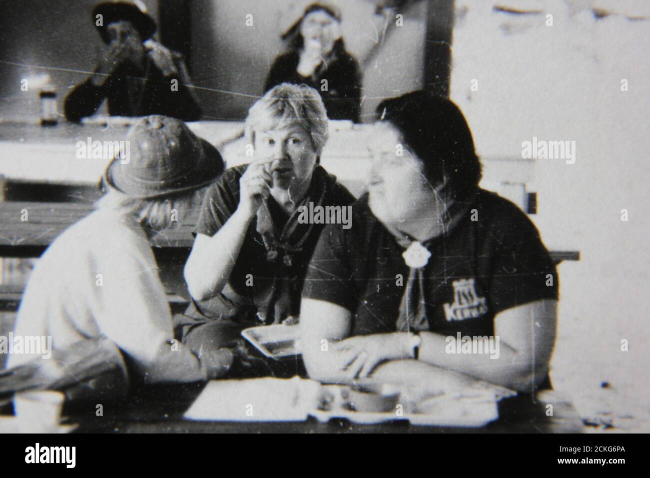 Feine 70er Jahre Vintage schwarz-weiß Fotografie von drei Mädchen Scout Berater mit einem freundlichen Chat in der Messehalle. Stockfoto