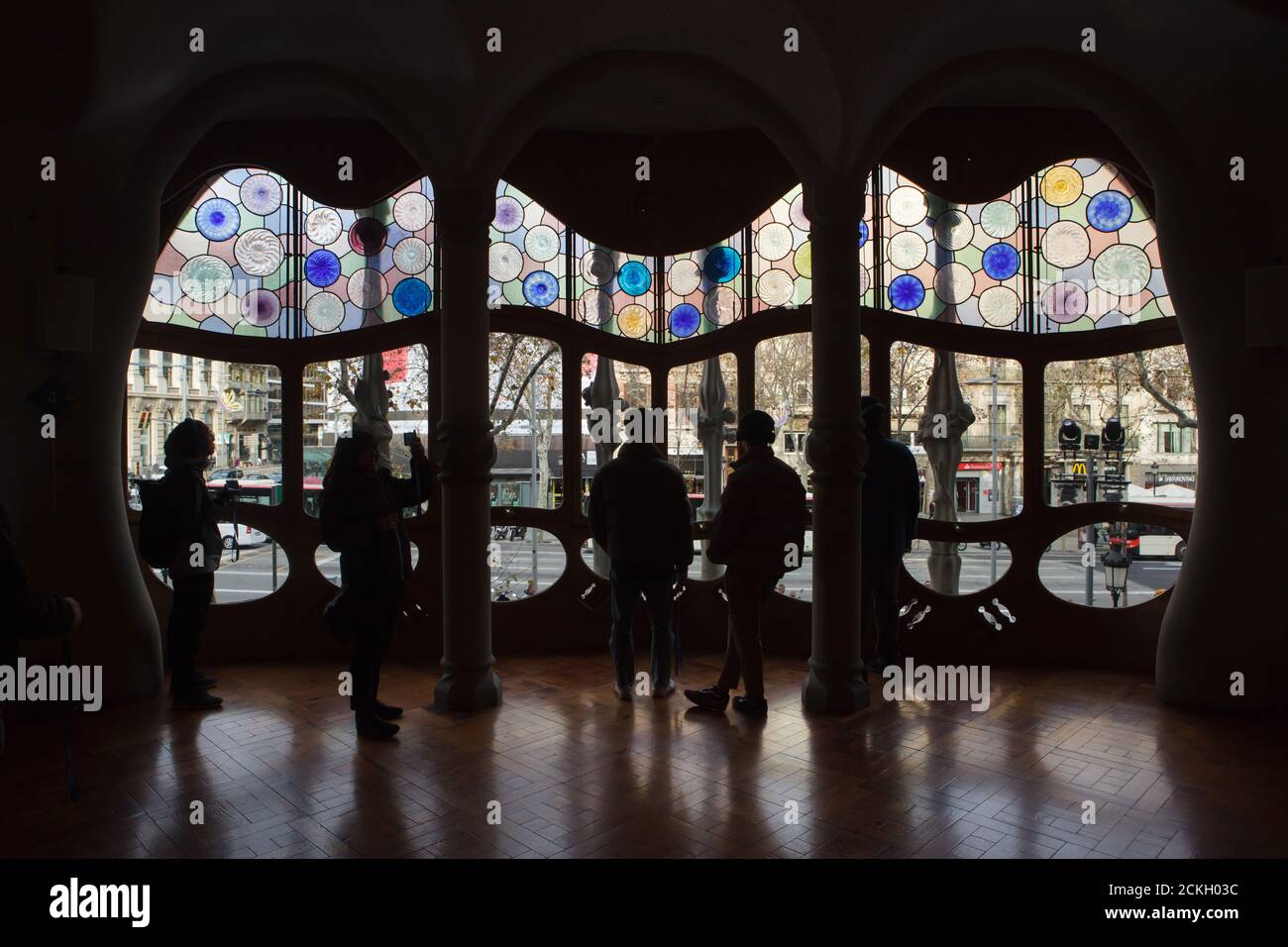 Besucher beobachten das große Buntglasfenster im zentralen Salon des edlen Bodens in der Casa Batlló in Barcelona, Katalonien, Spanien. Das Herrenhaus, das vom katalanischen modernistischen Architekten Antoni Gaudí für die Familie Batlló als Einnahmehaus sowie als private Familienresidenz entworfen wurde, wurde zwischen 1904 und 1906 erbaut. Stockfoto