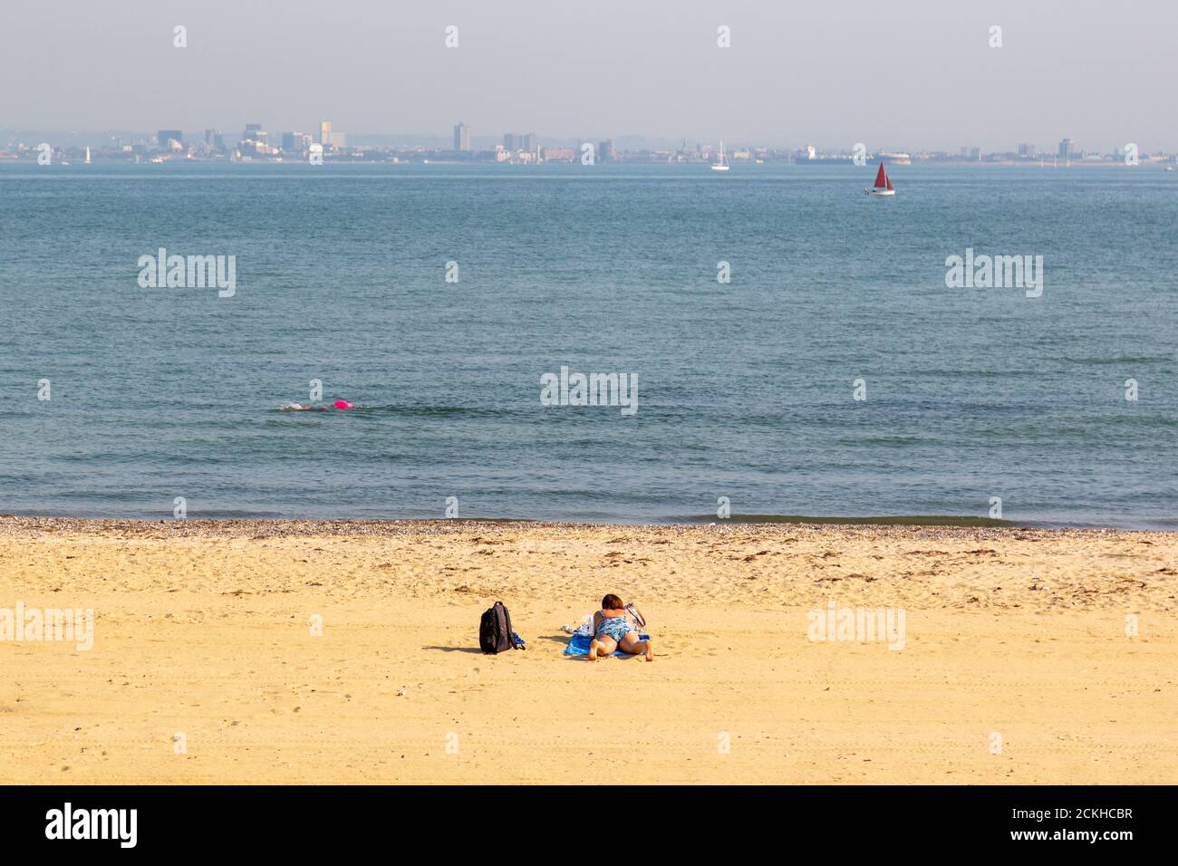 Eine Frau, die alleine an einem goldenen Sandstrand, Ryde, Isle of Wight, sonnenbaden geht Stockfoto