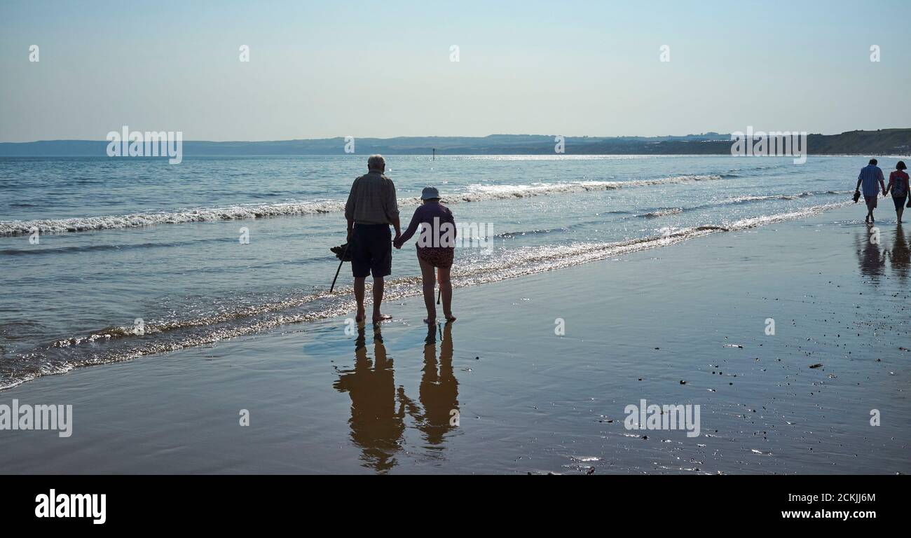 Ein altes Paar paddelt im Meer am Strand von Filey Cobble Landing, North Yorkshire Ostküste, Nordengland, Großbritannien Stockfoto