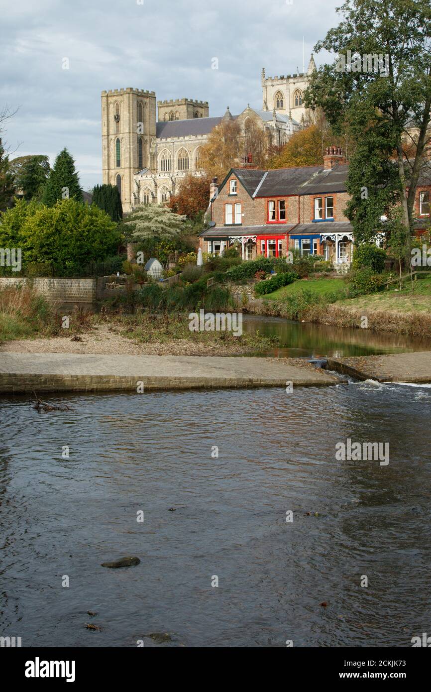 Der Fluss Skell mit Wohngebäuden und der Ripon Kathedrale im Hintergrund, Ripon, North Yorkshire, England, Vereinigtes Königreich. Stockfoto