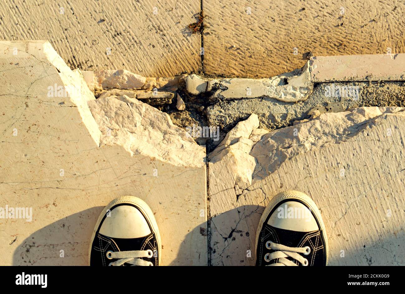 Alte Marmortreppe mit den Überresten einer gebrochenen Stufe Und die Spitzen eines Paares von Schwarz und Weiß Schuhe Stockfoto