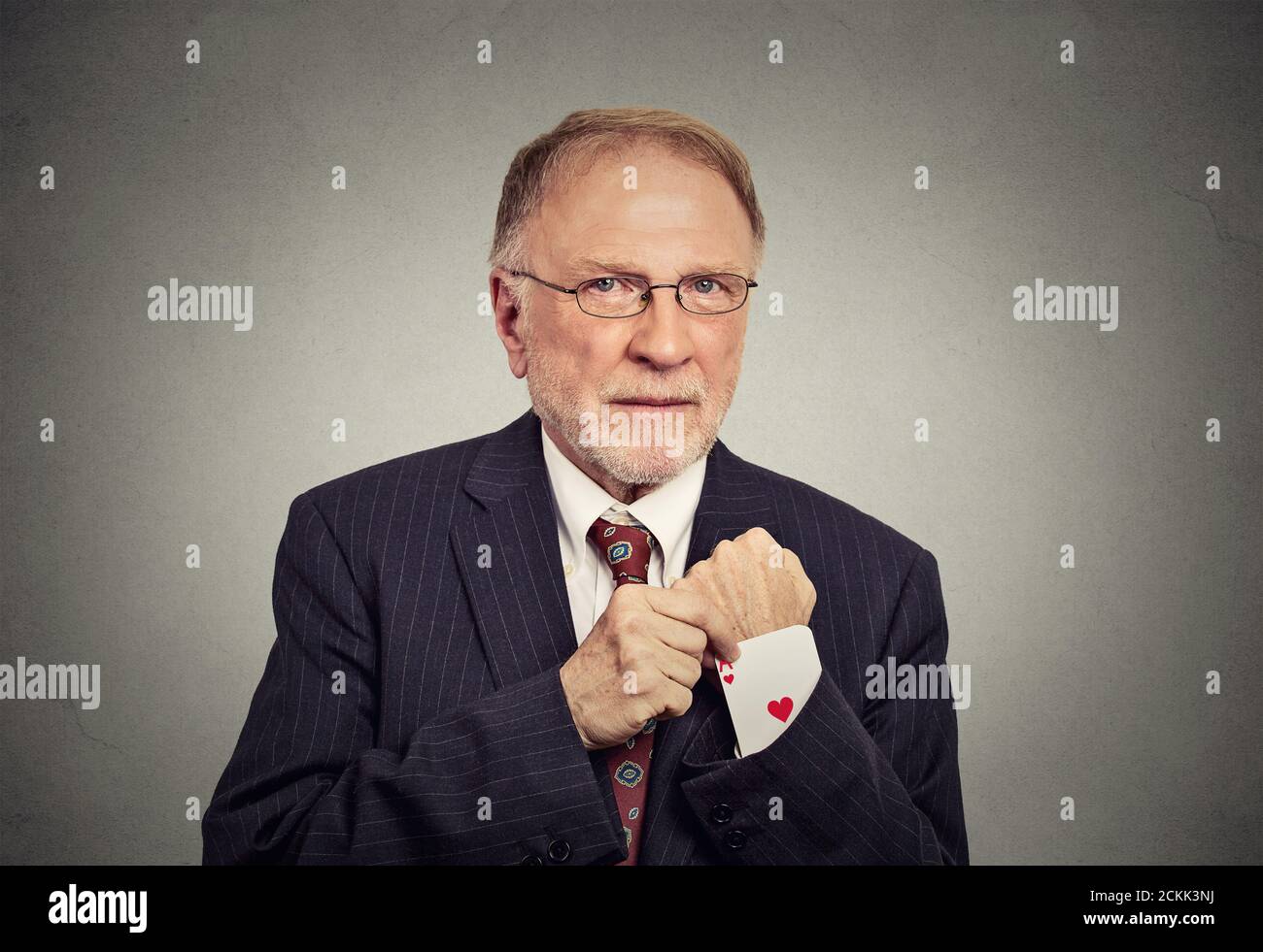 Nahaufnahme Porträt Senior Mann Deal Maker ziehen aus einem versteckten ace-Karte aus dem Anzug Jacke Ärmel isoliert auf grau Wandhintergrund Stockfoto