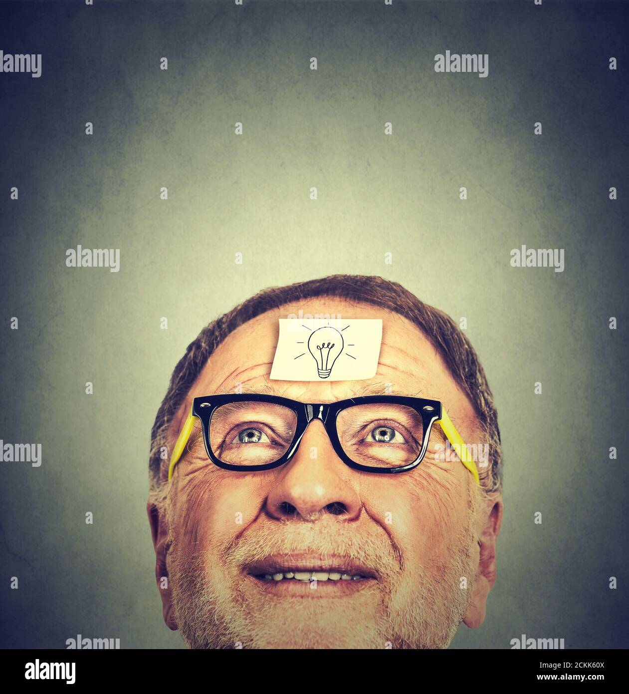 Portrait glücklich Senior Mann in einer Brille mit Idee Glühbirne nach oben schauen. Gesichtsausdruck des Menschen. Konzept der psychischen Gesundheit Stockfoto