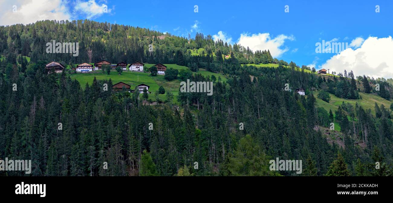 Panoramablick mit Berghöfen auf einer Waldlichtung auf einem Berghang im Lesachtal von Kärnten, Österreich Stockfoto