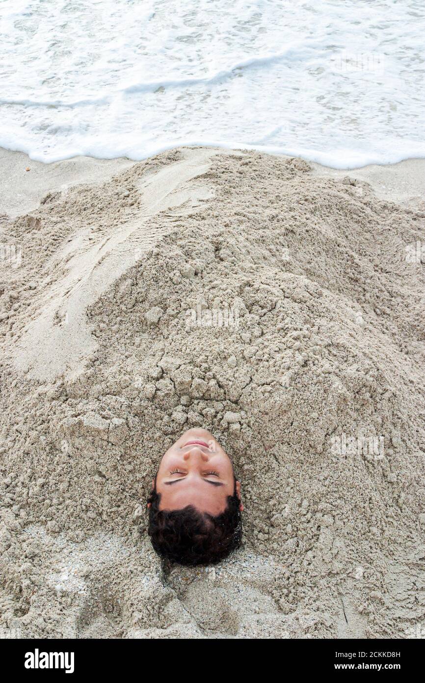Miami Beach, Florida, Atlantikküste, Küste am Meer, hispanischer Junge, Mann, vergrabener Sand durch Wassersurf, Teenager im Teenageralter Stockfoto