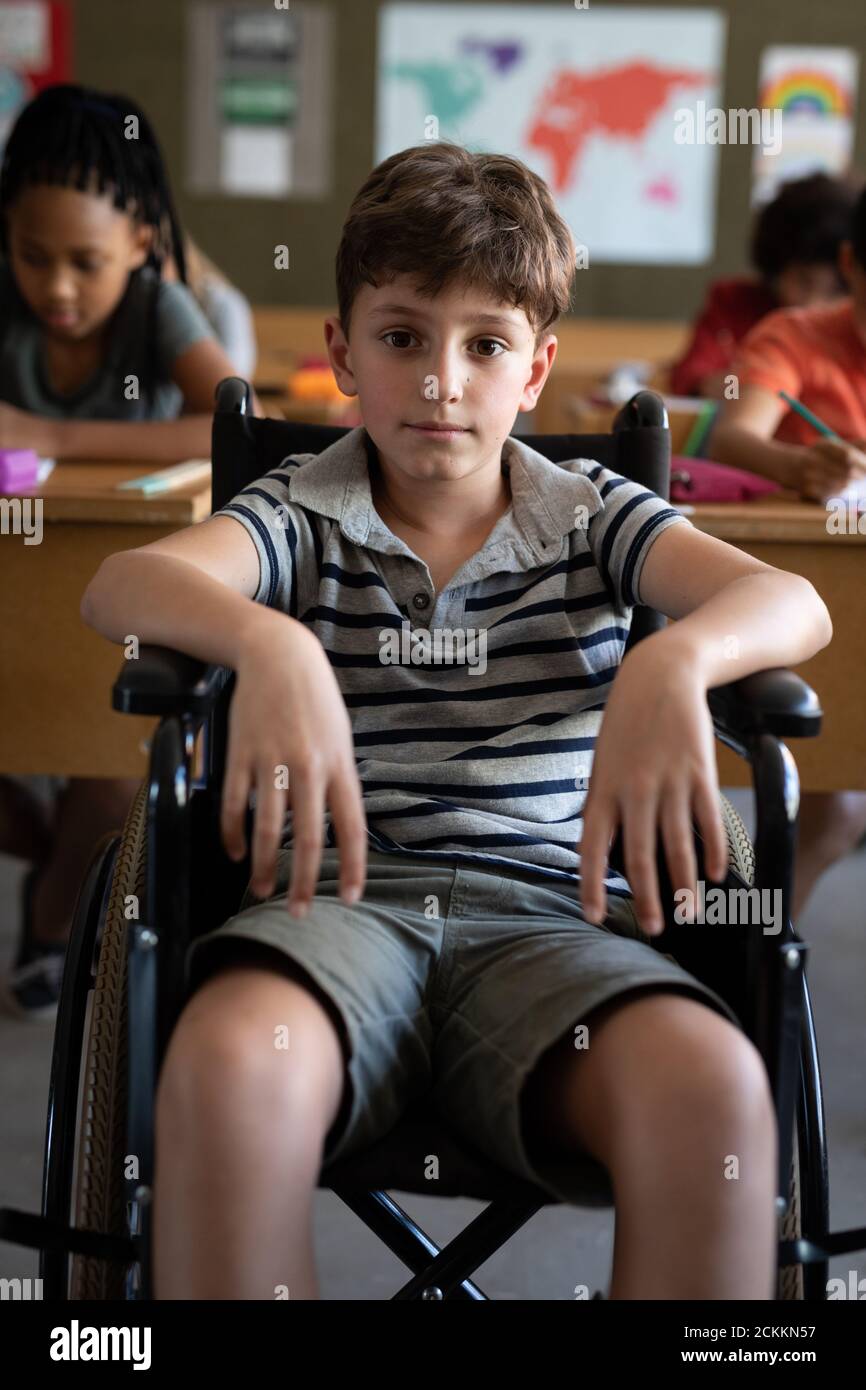 Porträt eines behinderten Jungen, der in seinem Rollstuhl in der Klasse sitzt In der Schule Stockfoto