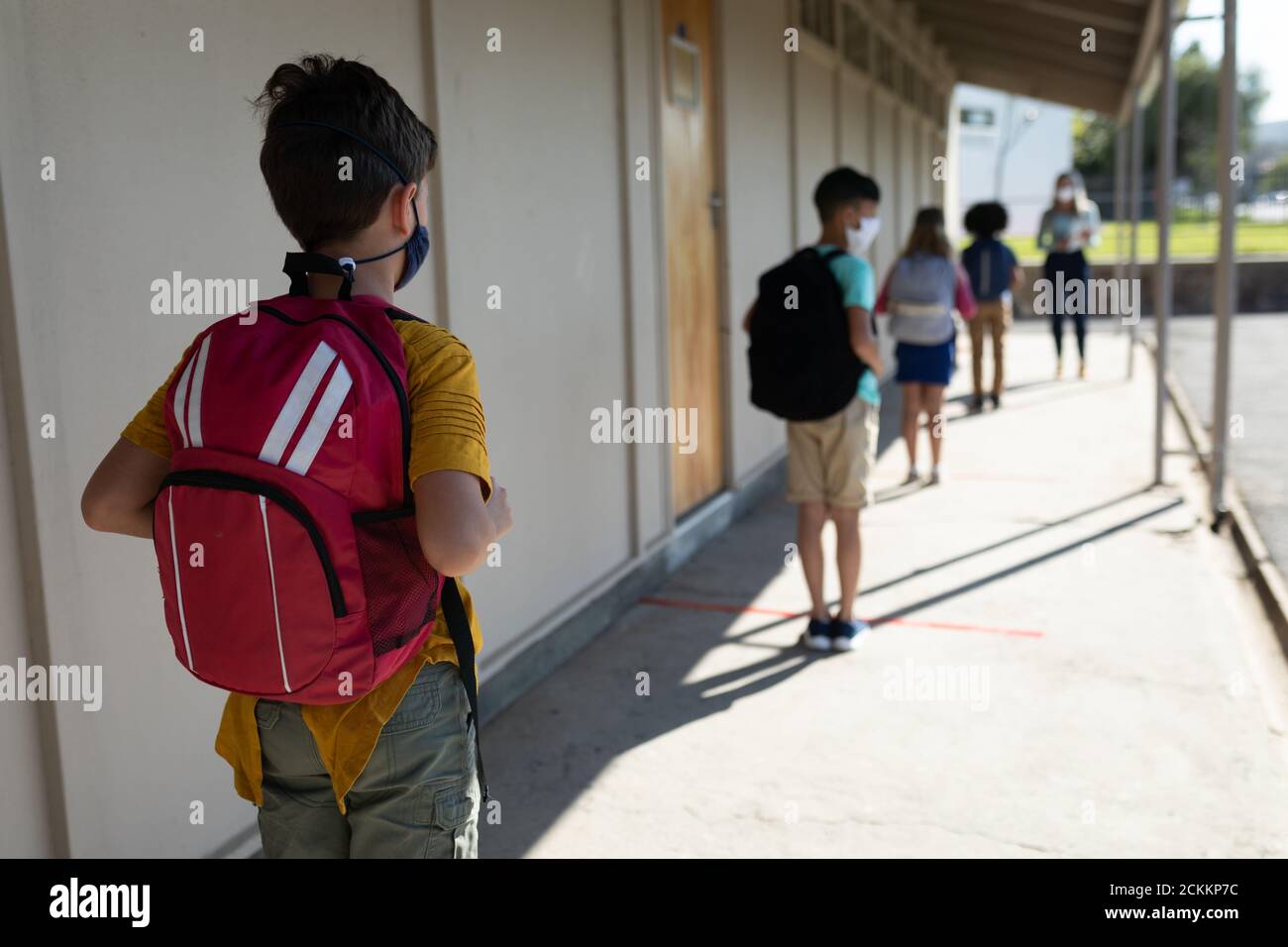 Rückansicht der Gruppe von Kindern tragen Gesichtsmasken Wartung Soziale Distanzierung in der Schule Stockfoto