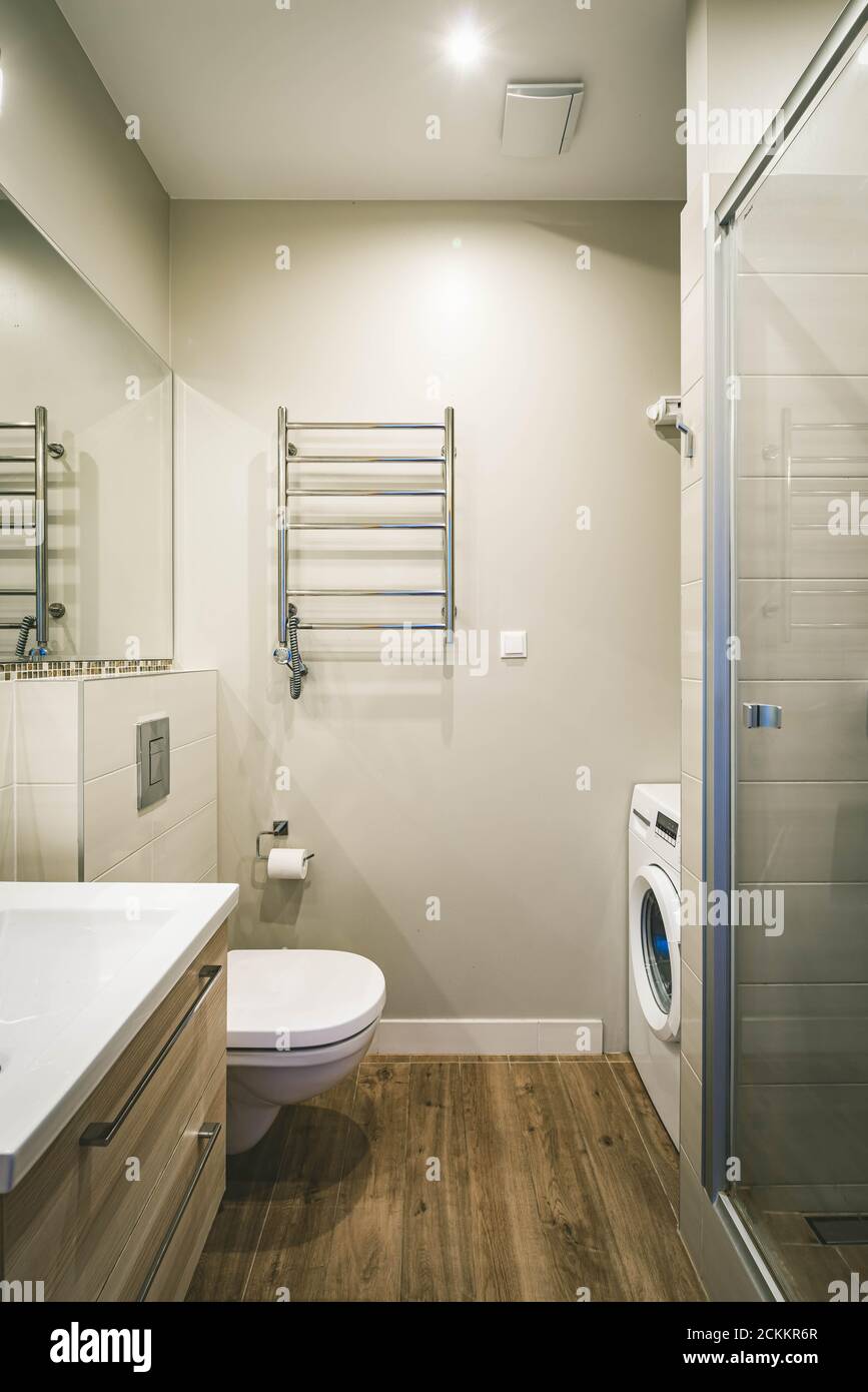 Moderne Innenausstattung des Badezimmers in Luxus-Wohnung. Waschbecken mit Holzschubladen. Duschkabine. Toilette. Waschmaschine. Stockfoto