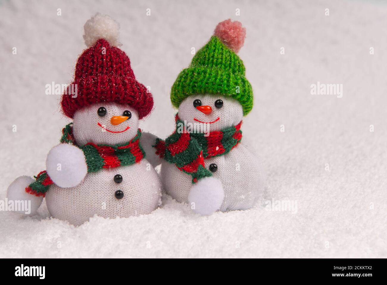 Zwei niedliche Schneemänner stehen im Schnee und lächeln bei Schneefall mit Kopierraum. Konzept weihnachten. Stockfoto