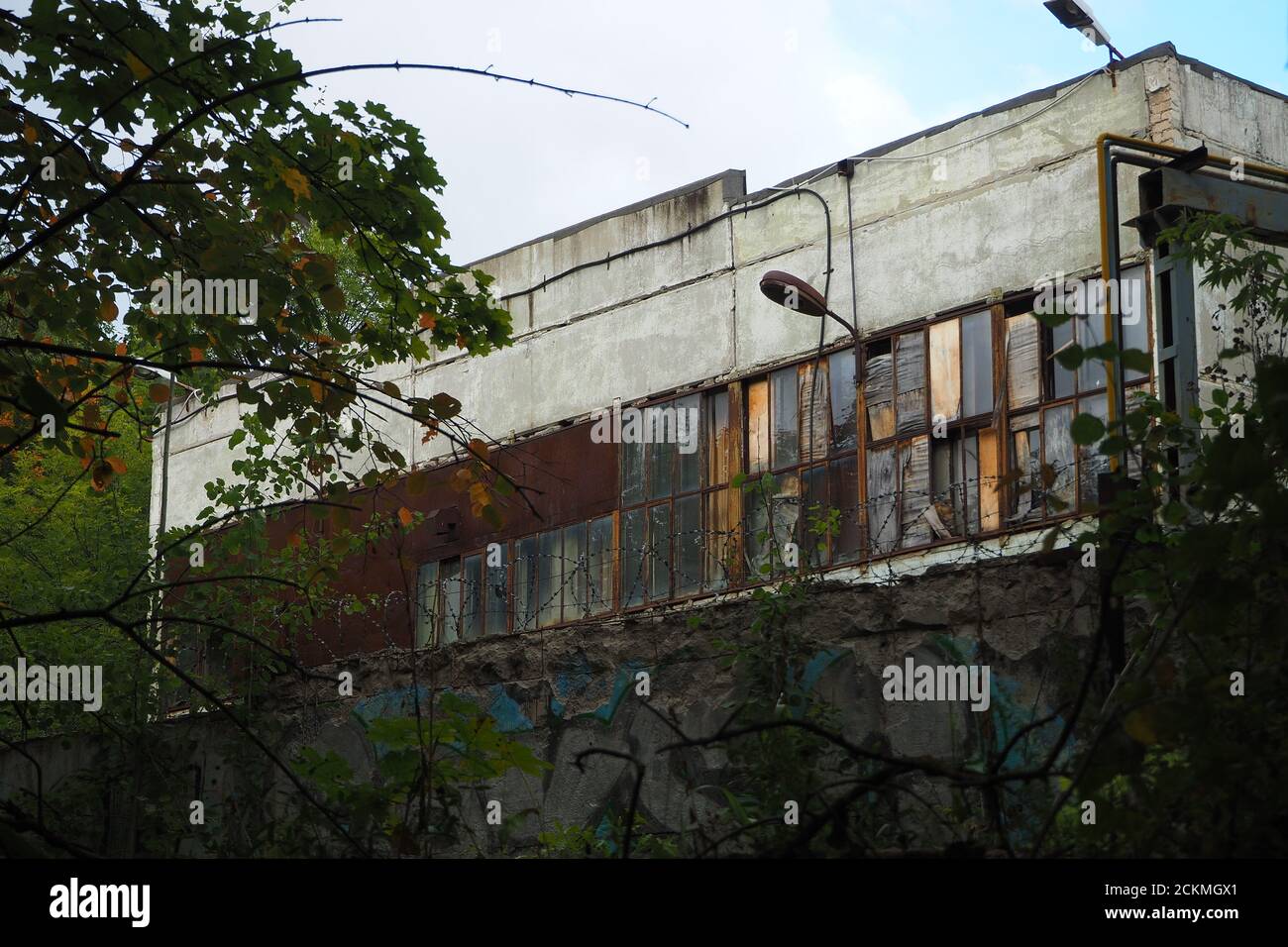 Verlassene Gebäude. Eine zerbröckelnde Struktur hinter dem Zaun. Stockfoto